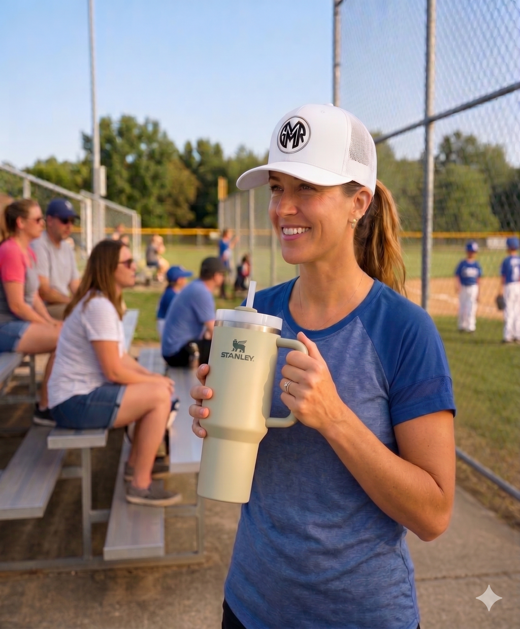 Woman wearing a GYMR hat at a sports event with people in the background